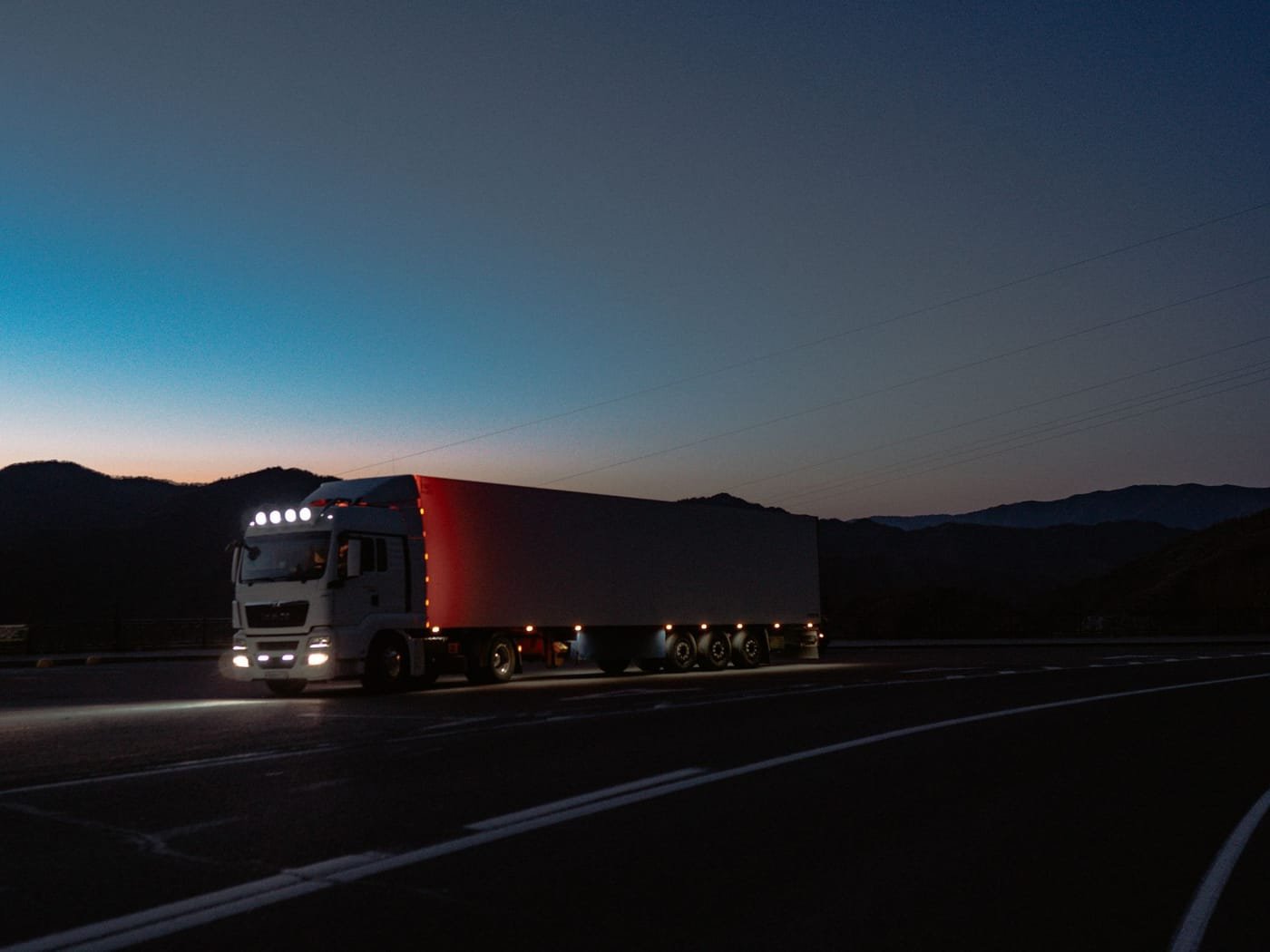Tractocamión circulando al anochecer con las luces encendidas