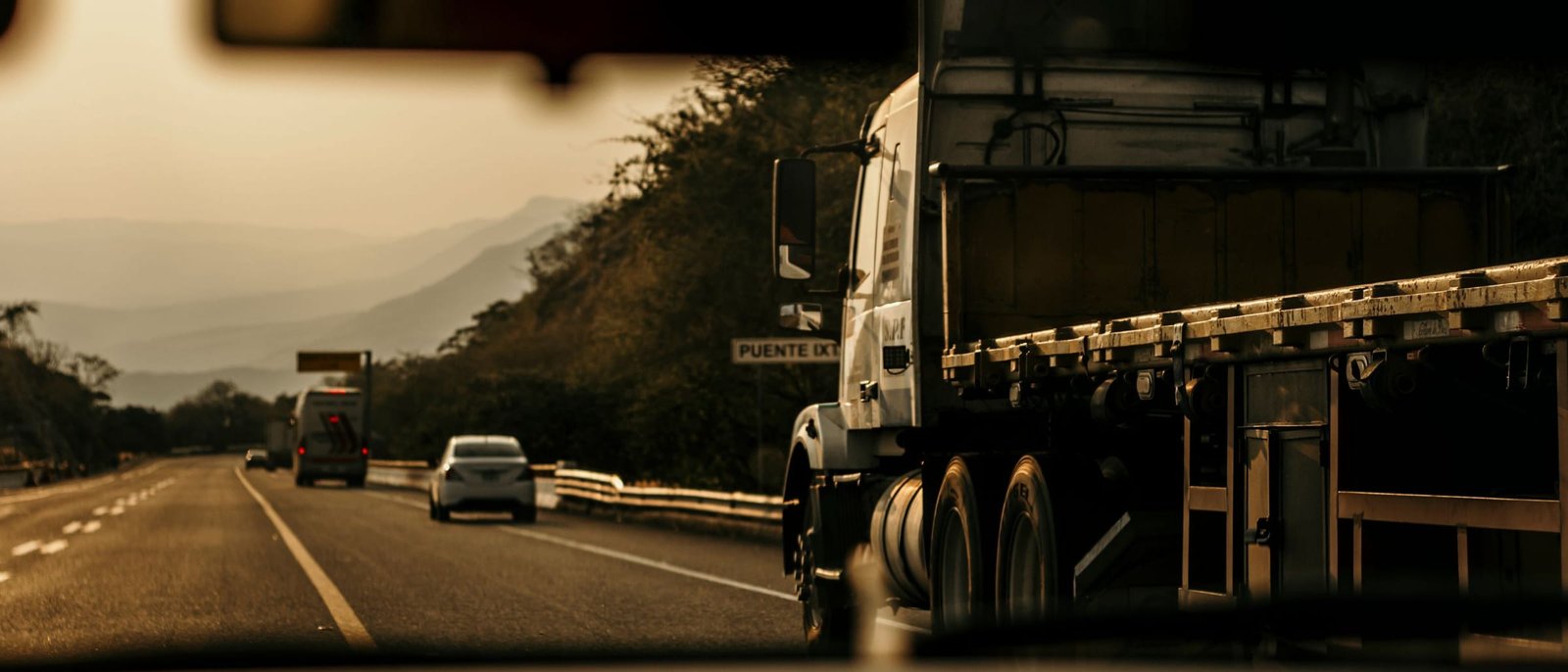 Camión de carga circulando por una carretera al atardecer
